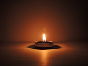 round ceramic bowl with lighted candle in a dark setting