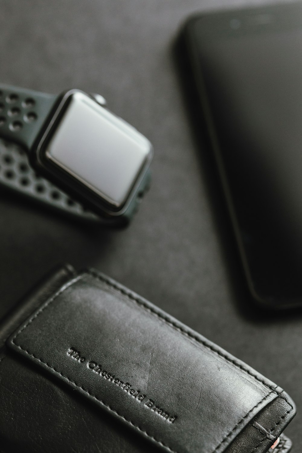 carteira de couro preto perto do espaço caso de alumínio preto Apple Watch com Nike Fuel Band cinza