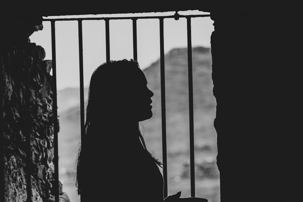 Sombra de mujer junto a la ventana de barrotes metálicos