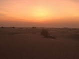 A vast desert landscape under a vibrant sunset sky.