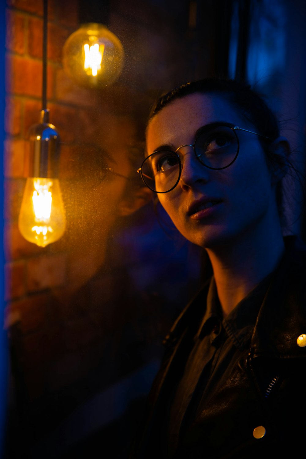 woman wearing clear eyeglasses across light bulbs