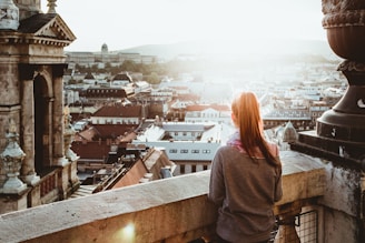woman standing on concrete building looking outside during daytime