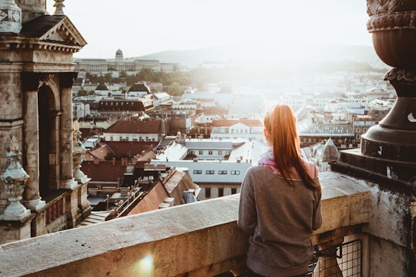 woman standing on concrete building looking outside during daytime