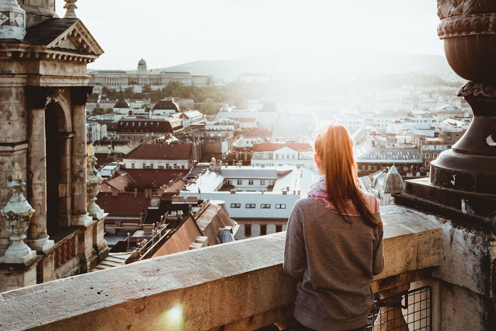 woman standing on concrete building looking outside during daytime