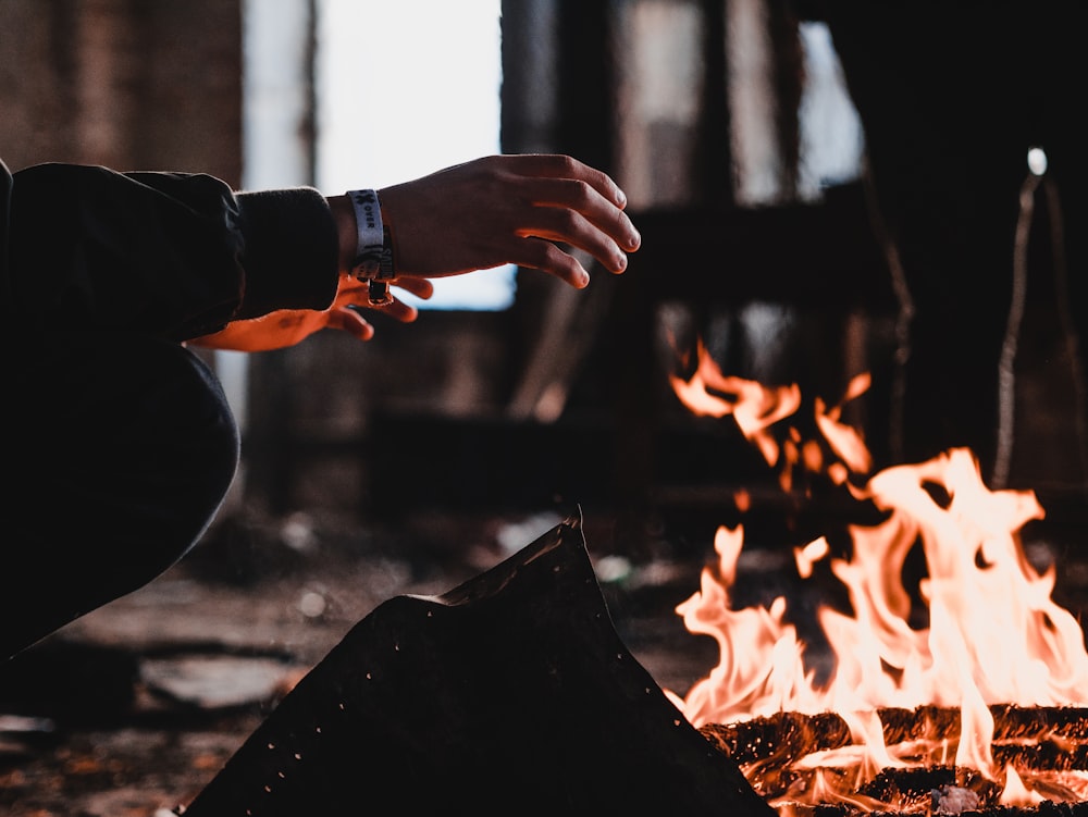 Homme portant une veste noire près d’un feu de joie