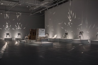 A dimly lit installation featuring layered sculptures and projected abstract visuals.