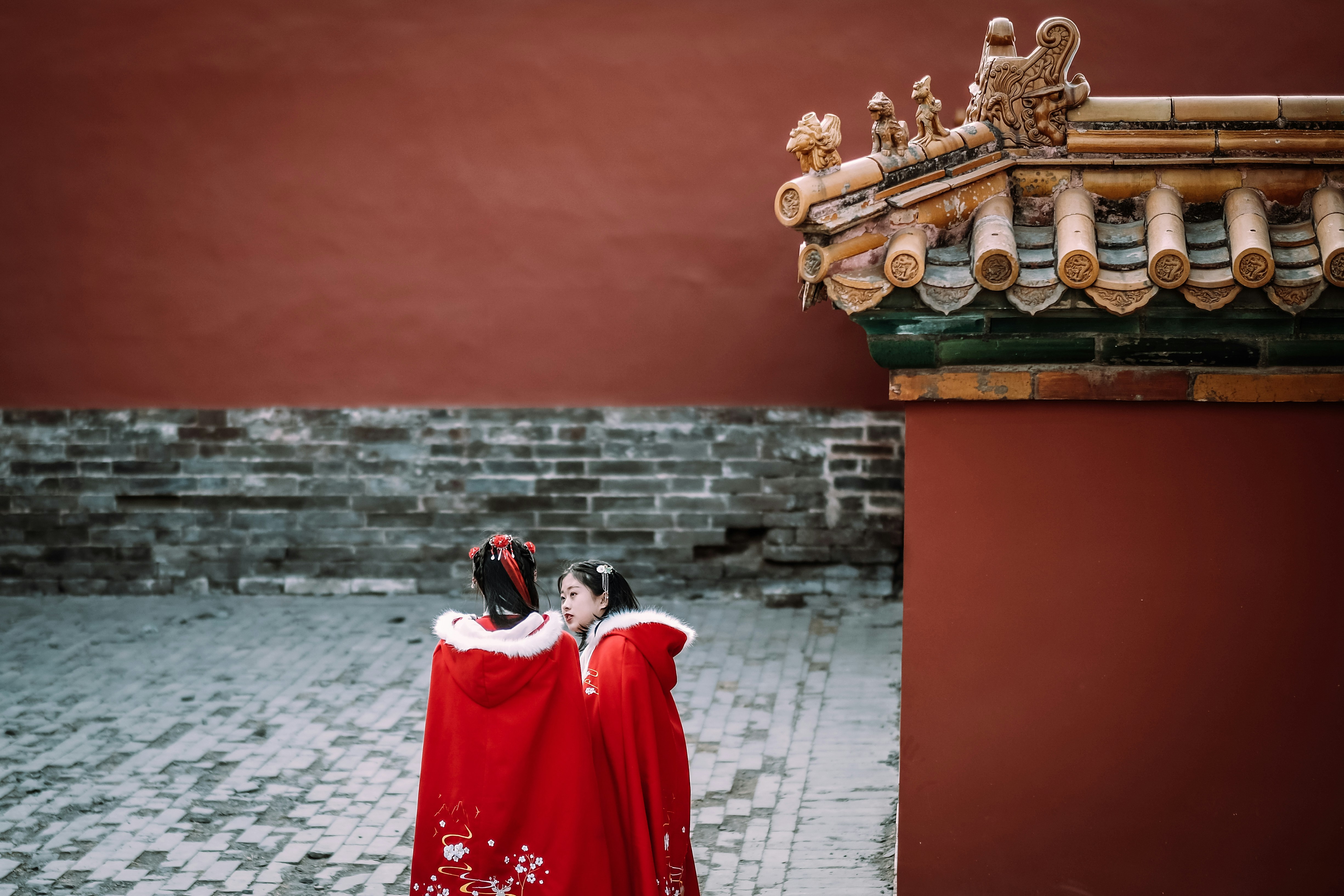 two women standing on gray brick pavement
