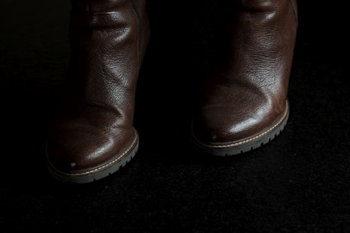 A pair of women's boots standing on a cobblestone street, highlighting their durable sole and elegant silhouette.