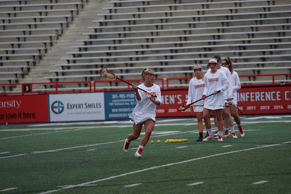 women on field playing lacrosse during daytime