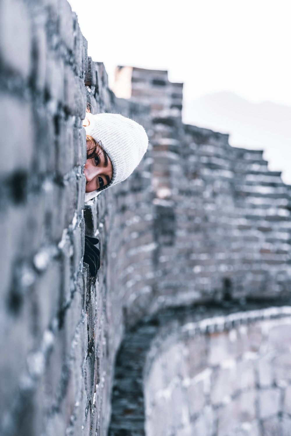 person peeking behind concrete wall