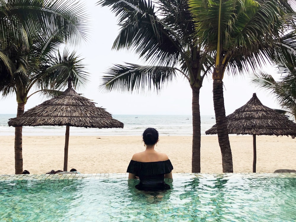 woman in pool looking on sea