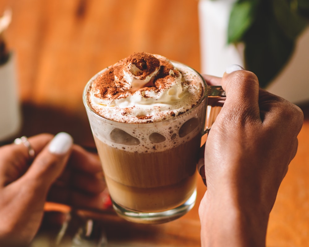 Persona che tiene la tazza con la bevanda al cioccolato e la crema