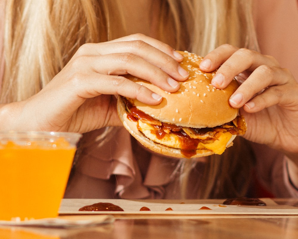 woman holding hamburger on table
