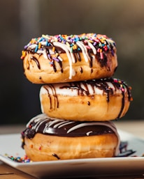 three chocolate-coated donuts with sprinkles