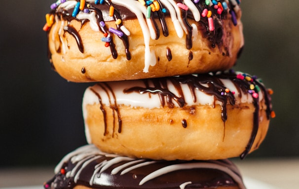 three chocolate-coated donuts with sprinkles