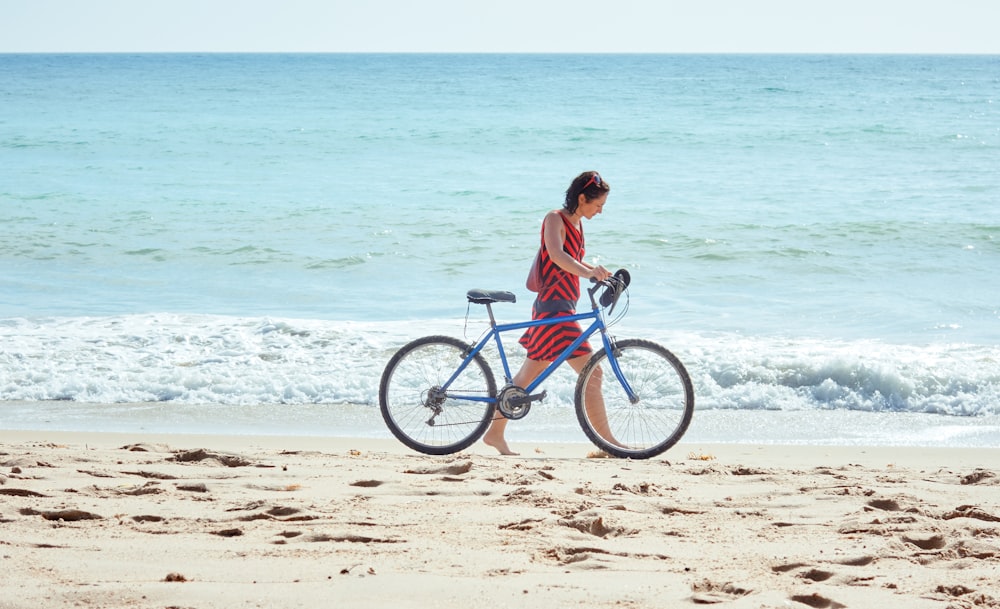 femme marchant sur le bord de mer avec un vélo