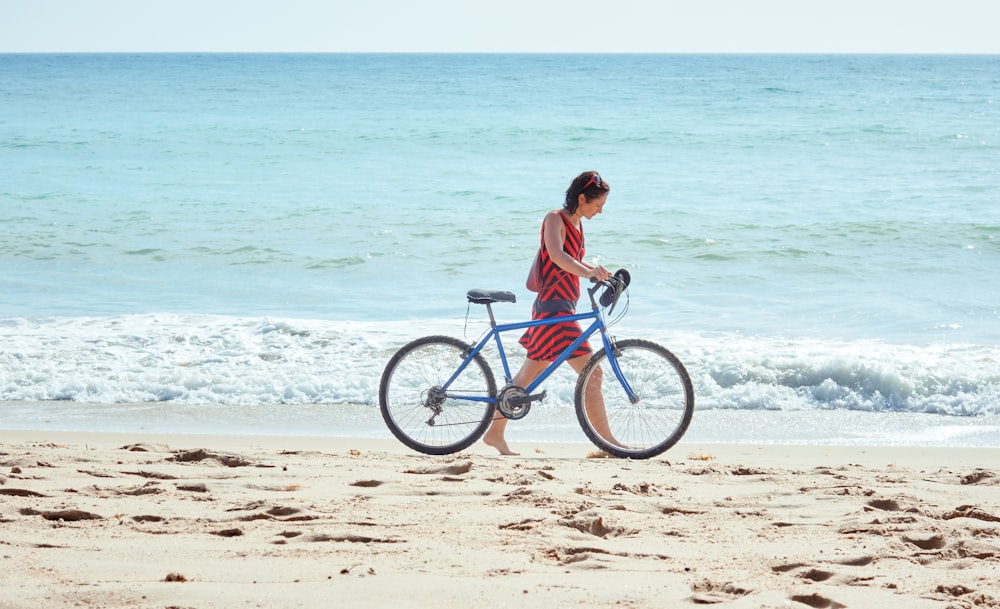 mulher que caminha na praia com bicicleta
