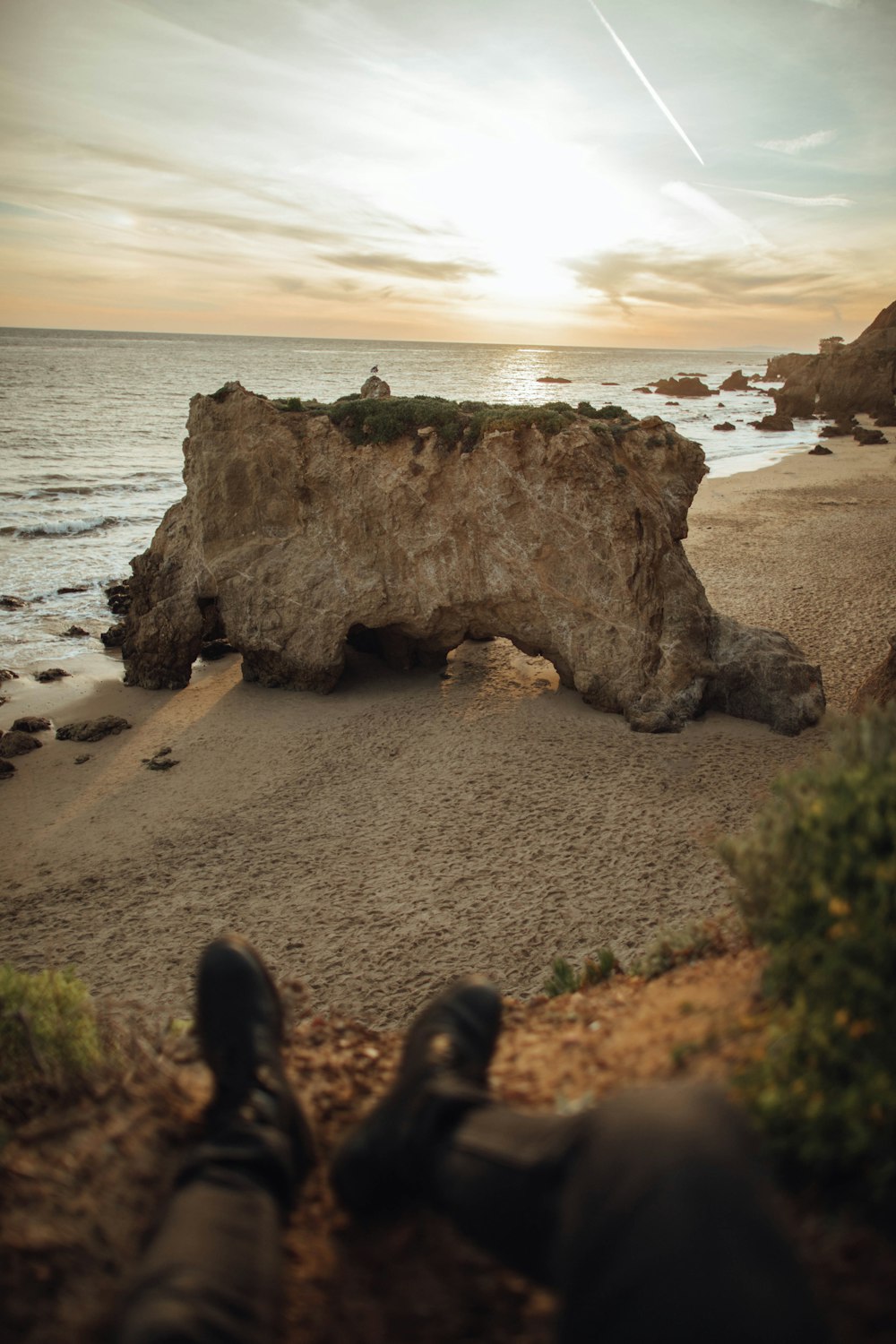 person sitting on cliff near beach