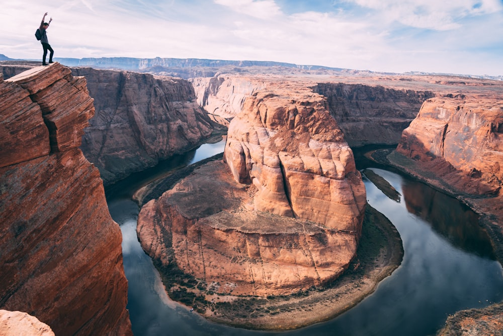 man standing by cliff of horseshoe canyon during daytime