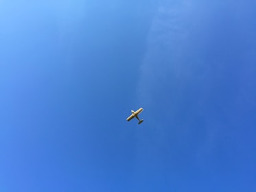 A young pilot confidently taking off in a light aircraft against a clear blue sky.