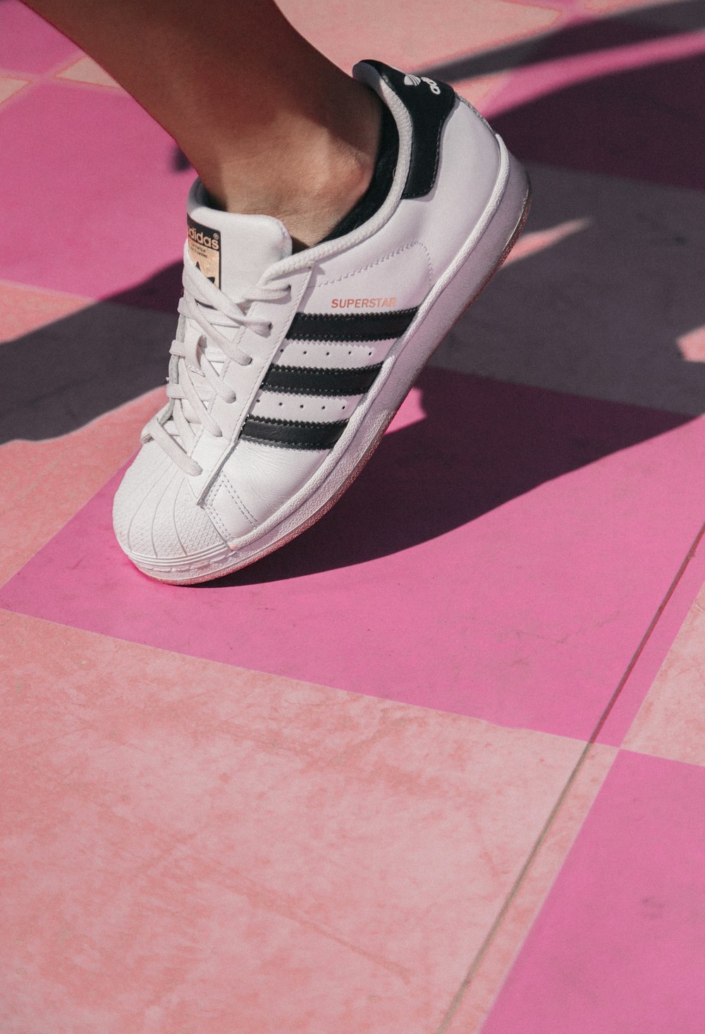 a close up of a person's shoes on a pink and black checkered