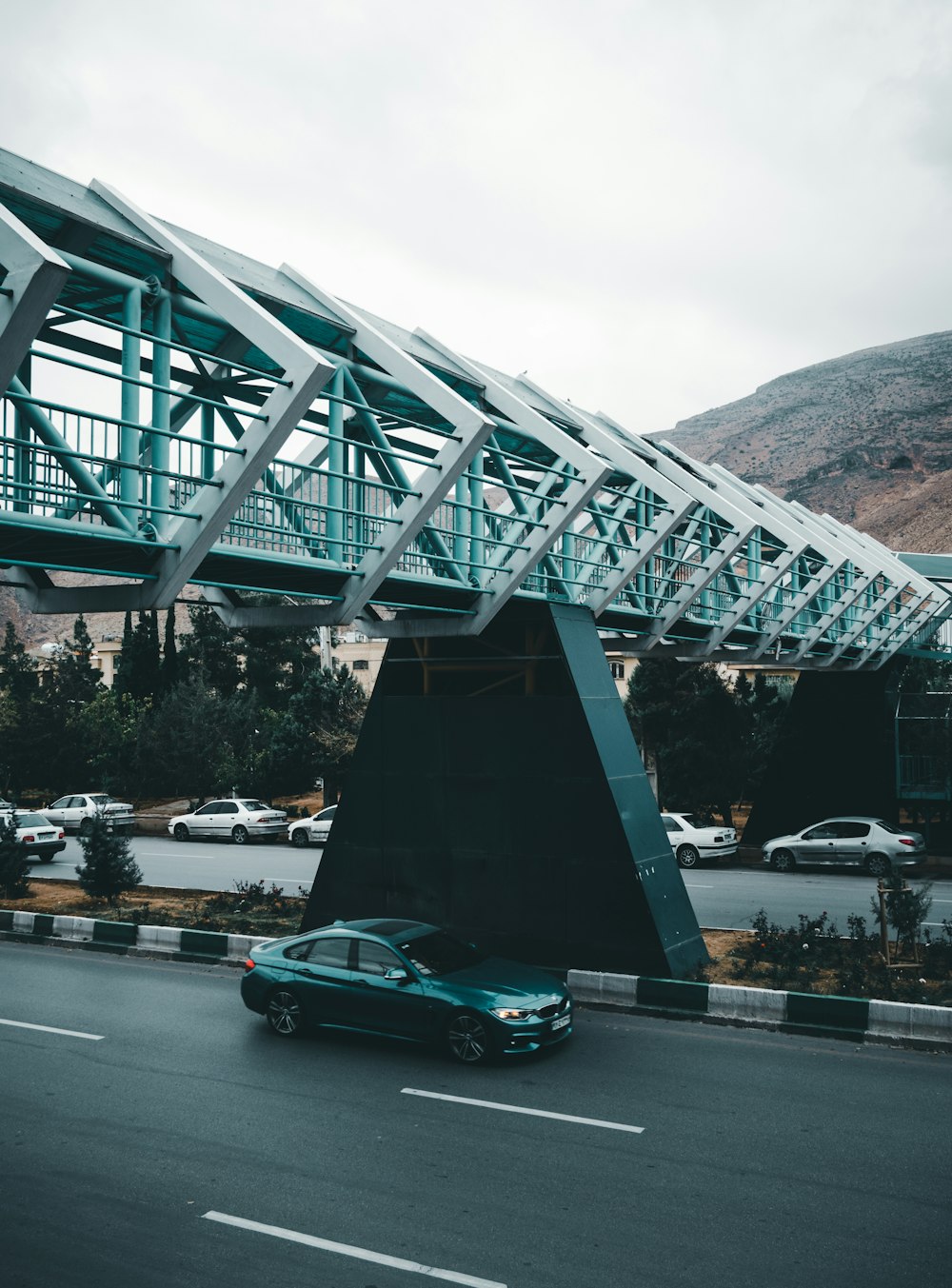 black sedan passing under overpass bridge