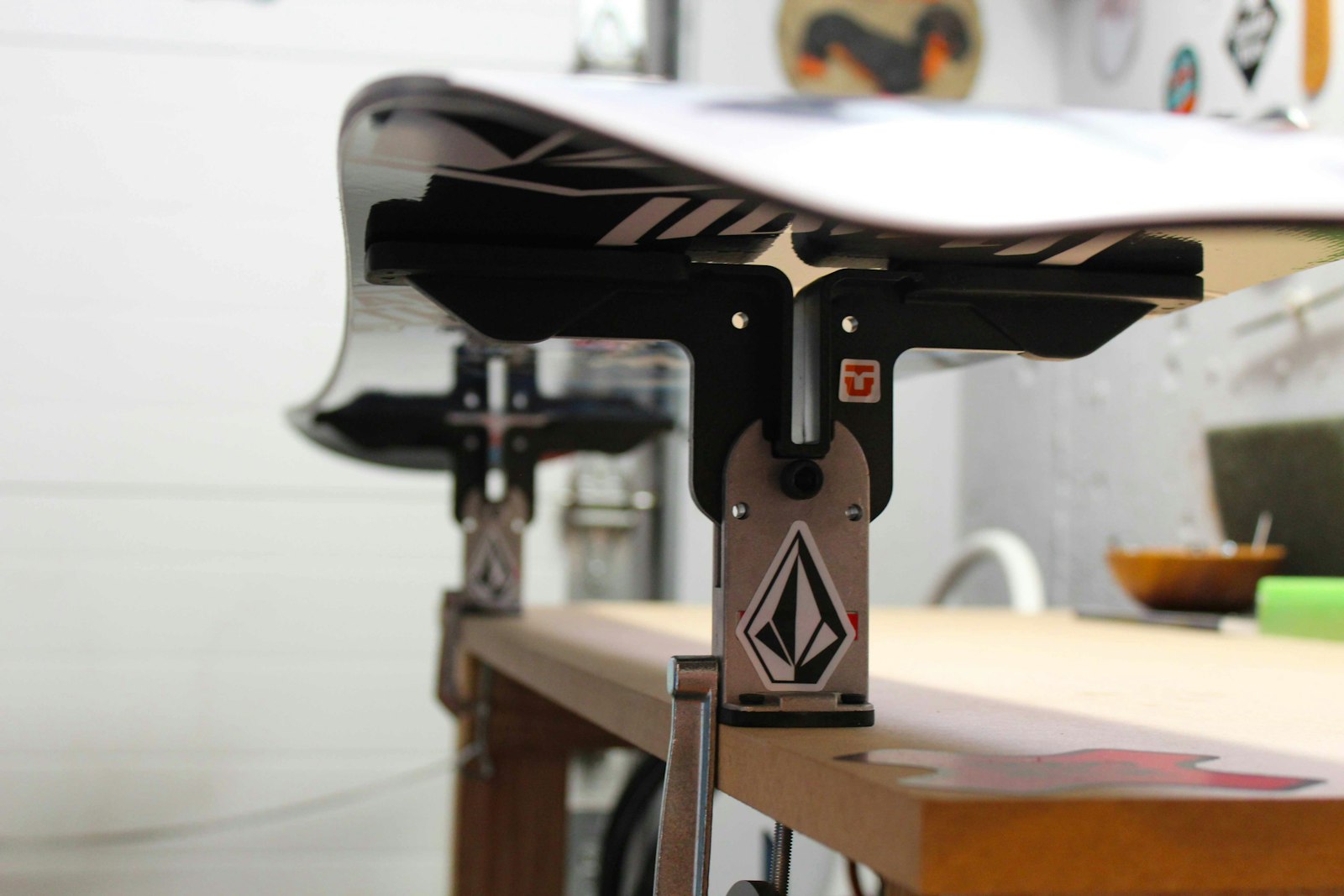 A snowboard clamped base-up in a tuning vise on the bench