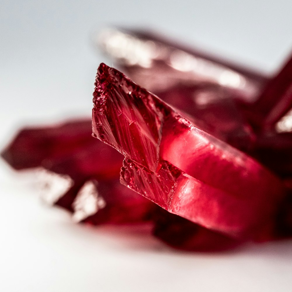 a close up of some red crystals on a white surface