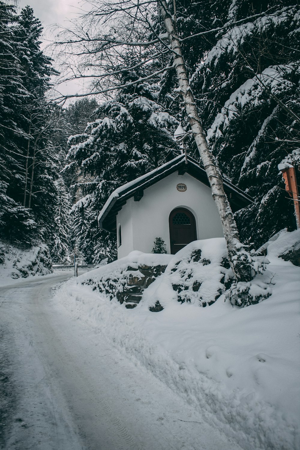 a small white house in the middle of a snowy forest