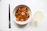 A vibrant bowl of steaming Asian noodles with fresh vegetables and chopsticks.