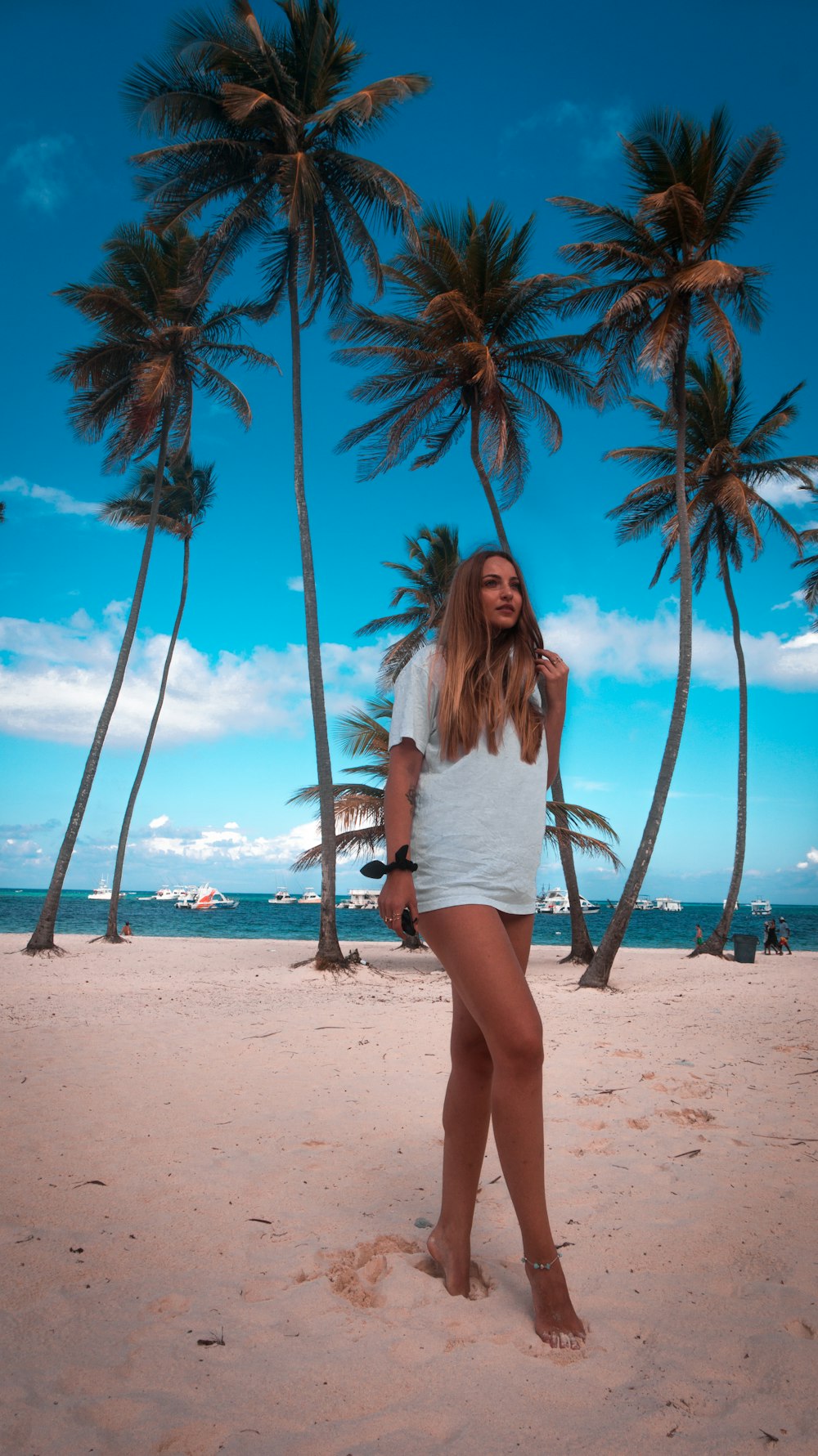 woman standing on sand near tall trees