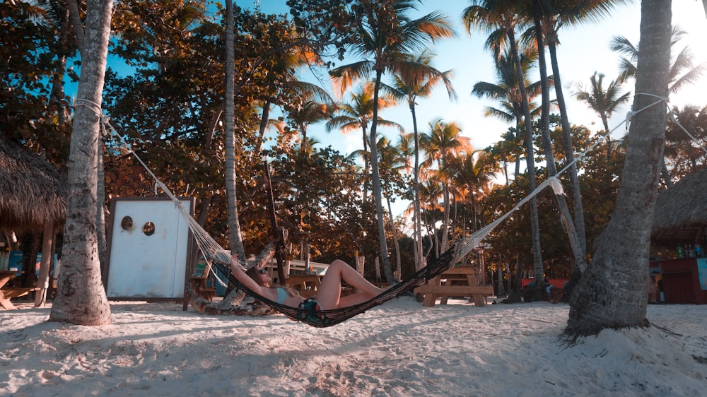 woman lying on hammock beside beach