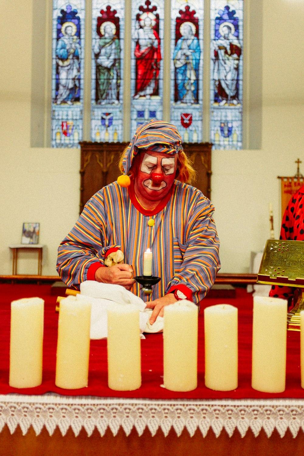 clown holding candle inside church