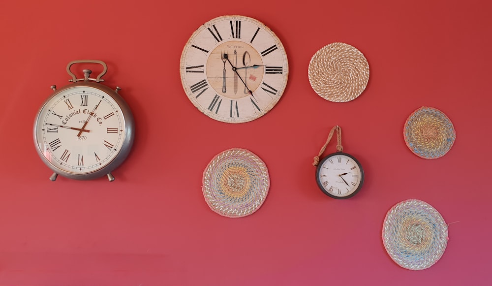 three round analog clocks and round gray mats