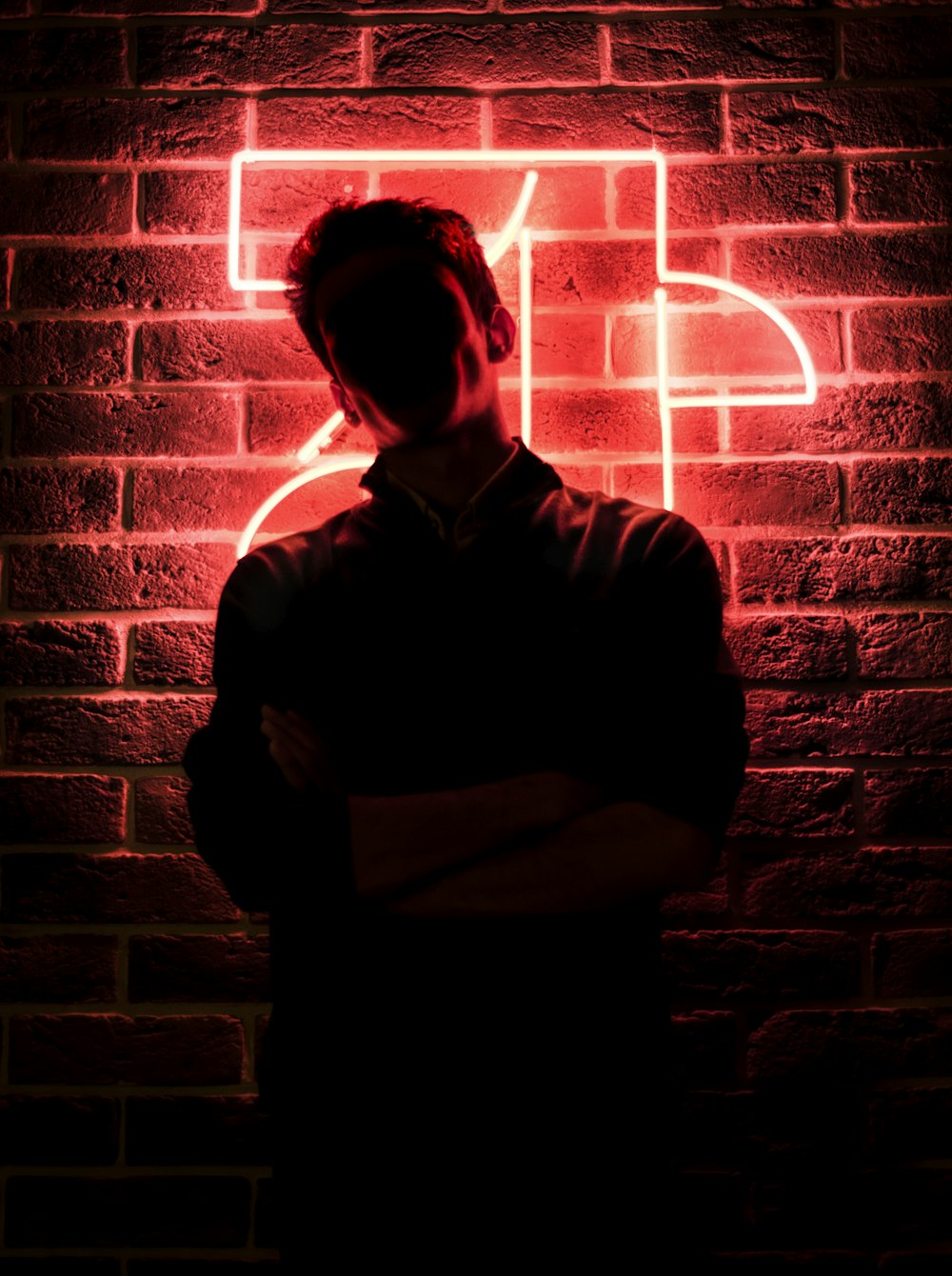 赤い明かりの壁のそばに立つ男
