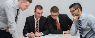 four men looking to the paper on table