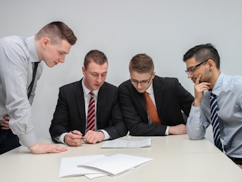 four men looking to the paper on table