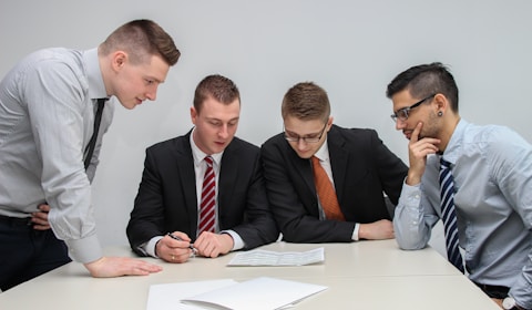 four men looking to the paper on table