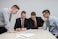 four men looking to the paper on table
