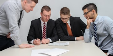 four men looking to the paper on table