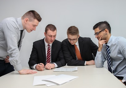 four men looking to the paper on table