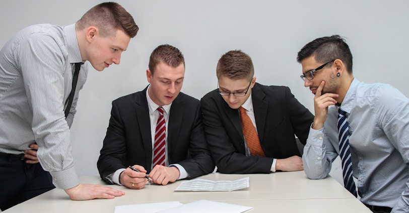 four men looking to the paper on table