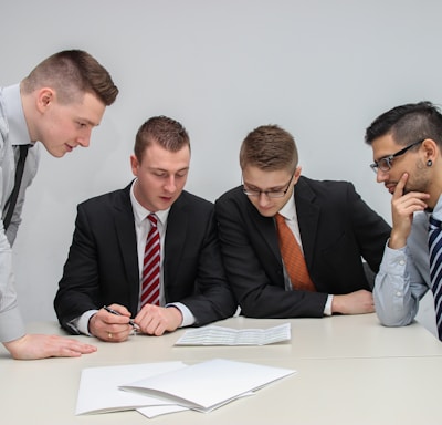 four men looking to the paper on table