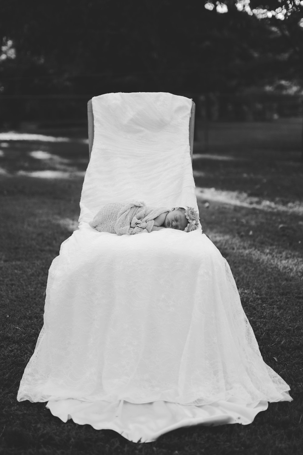 greyscale photo of newborn baby sleeping on white clothed seat