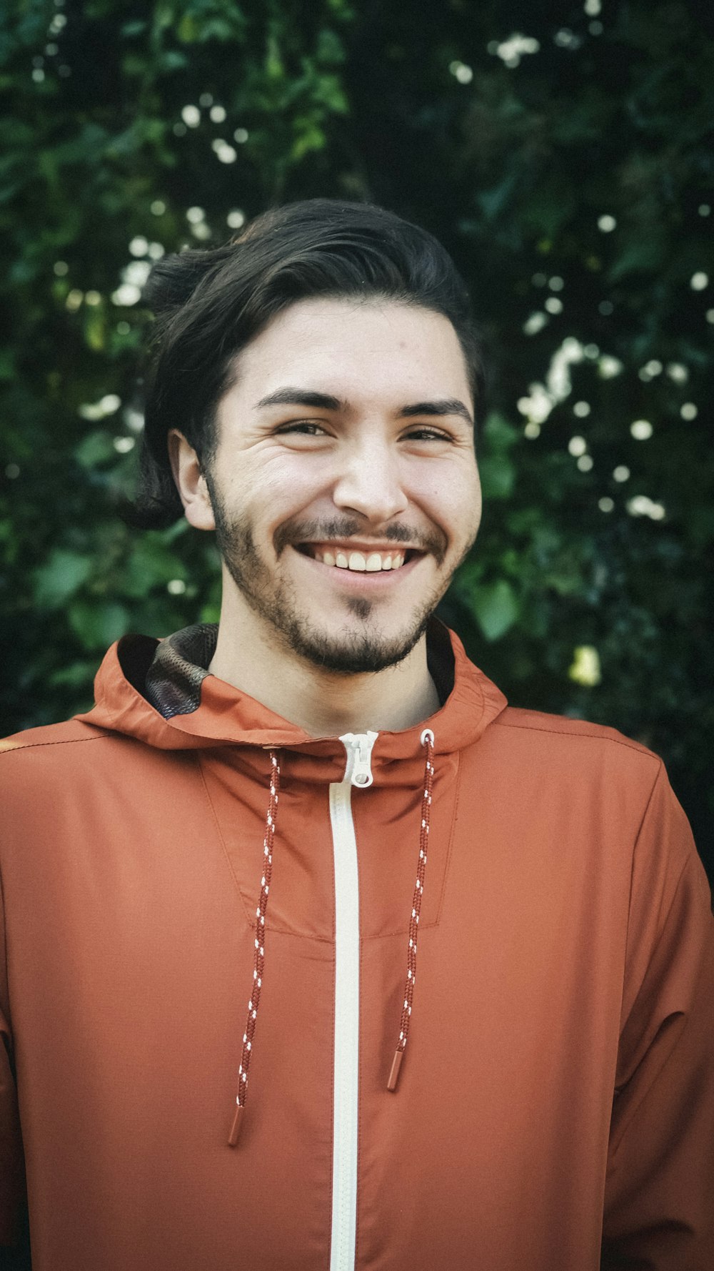 smiling man wearing orange zip-up jacket