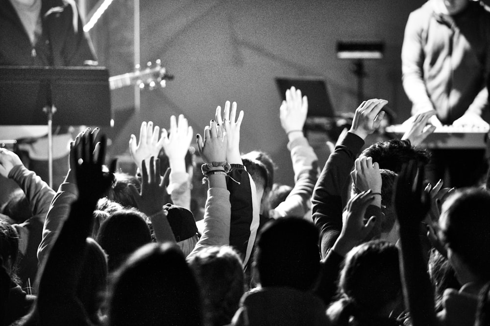 greyscale photo of crowd raising their hands high during concert
