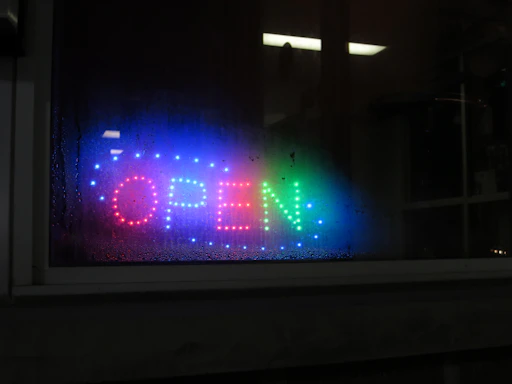 A bright LED monitor displaying a vibrant storefront message at night.