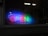 A brightly lit LED sign displays the word 'OPEN' in red, blue, and green colors. The lights are shining through a fogged-up window, indicating a warm atmosphere inside against a cooler exterior.