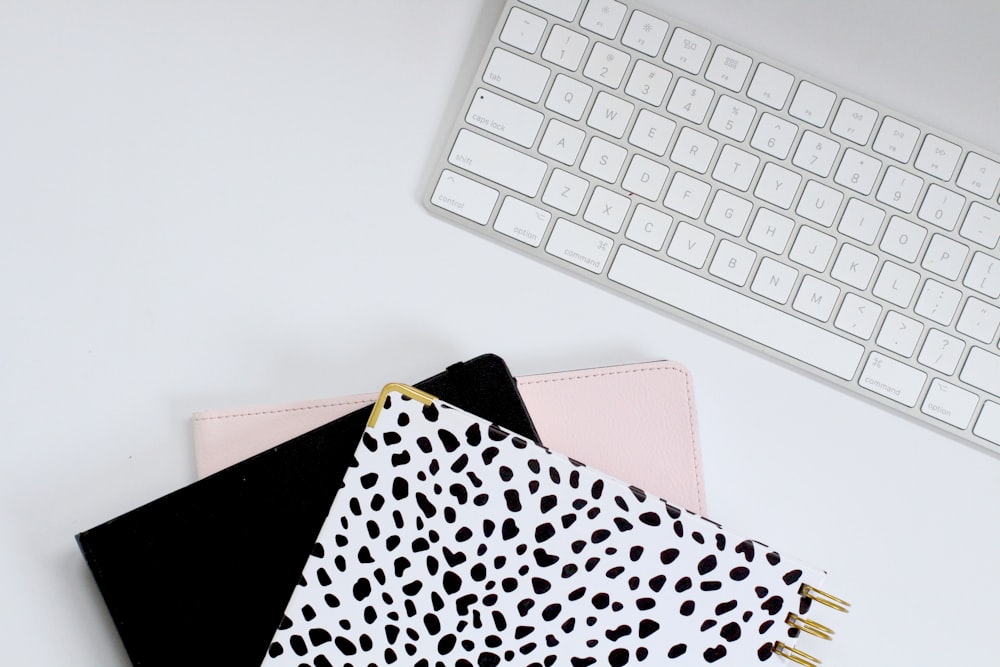 three notebooks sitting next to a keyboard on a desk