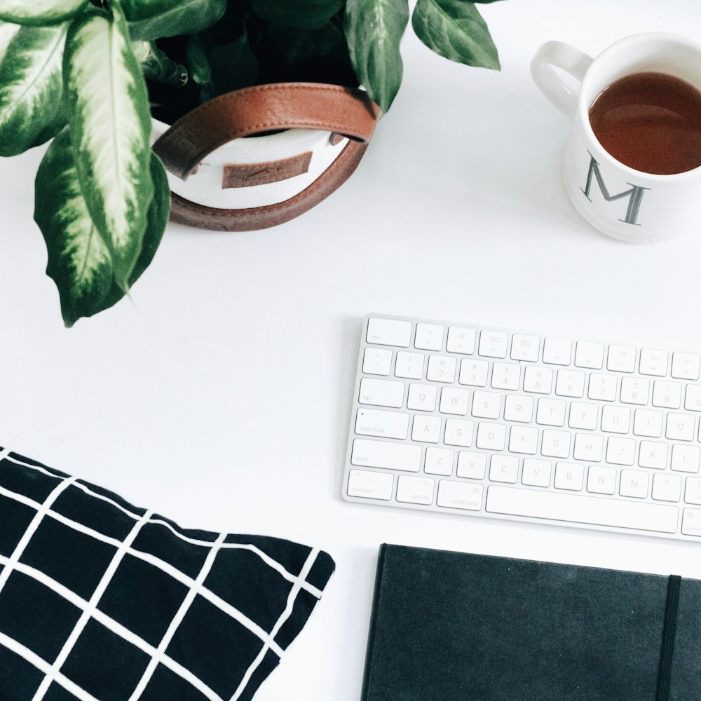 Apple Magic keyboard beside white ceramic mug